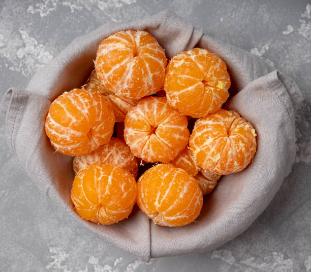 Sweet and juicy mandarins in bowl on the gray rustic background. Christmas background. Selective focus. Shot from above.